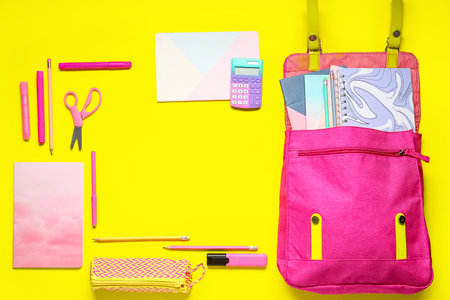 Frame made of school backpack and different stationery on yellow backgroundの写真素材