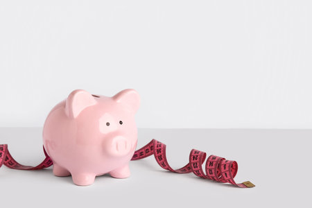 Piggy bank with measuring tape on white background