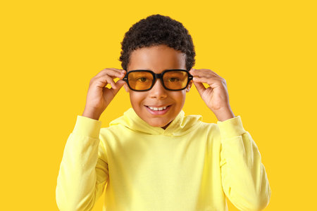 African-American little boy in sunglasses on yellow background, closeup