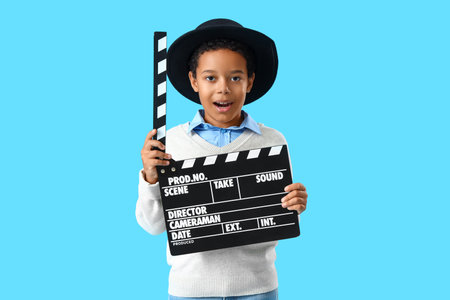 African-American little boy with movie clapper on blue backgroundの写真素材