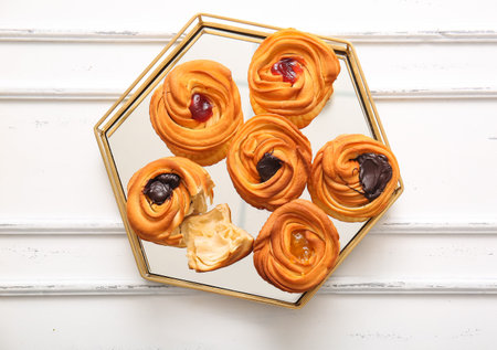 Tray of tasty cruffins with chocolate and jam on white wooden background