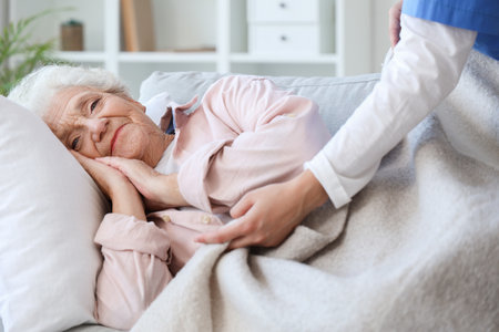 Female nurse caring about lying senior woman at homeの写真素材