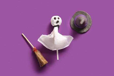 Sweet lollipop with witch hat and broom for Halloween party on purple backgroundの写真素材
