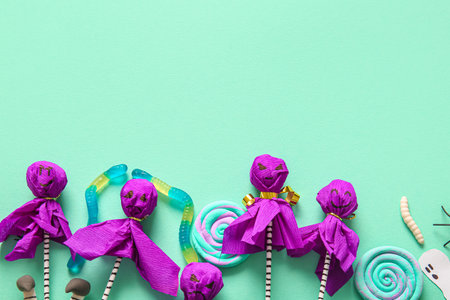 Sweet lollipops with jelly worms and candies for Halloween party on turquoise backgroundの写真素材