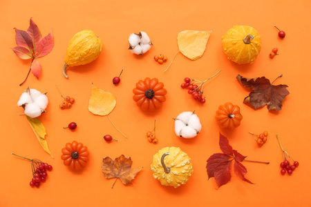 Beautiful composition with candles in shape of pumpkin and autumn leaves on orange backgroundの写真素材