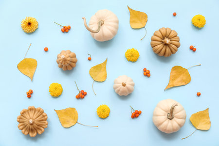 Beautiful composition with candles in shape of pumpkin and autumn leaves on blue backgroundの写真素材