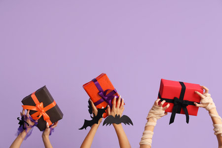 Women with Halloween gifts on lilac backgroundの写真素材