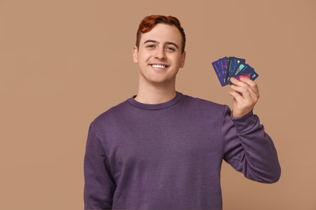 Young man with credit cards on brown backgroundの写真素材