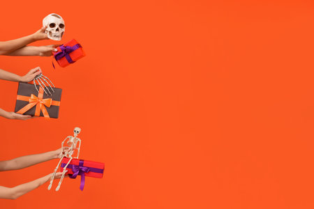 Women with Halloween gifts and skeletons on orange backgroundの写真素材
