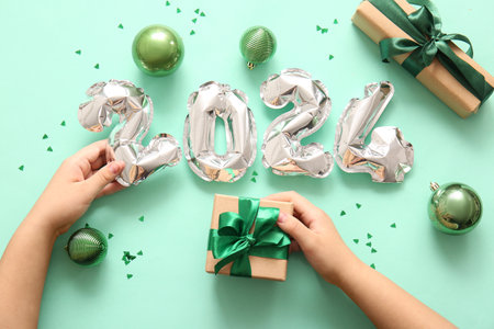 Woman with figure 2024 made of balloons, Christmas balls and gifts on green backgroundの写真素材