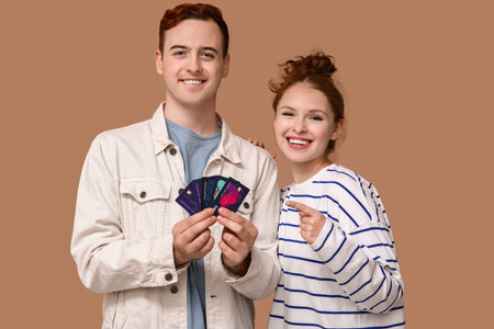 Young couple pointing at credit cards on brown backgroundの写真素材