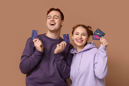 Young couple with credit cards on brown background