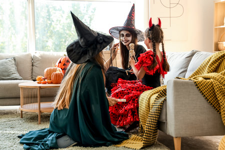 Mother painting face of her little daughter for Halloween at homeの写真素材