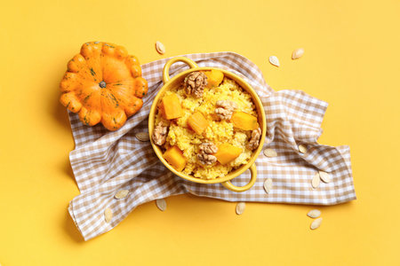 Pot of tasty millet porridge with pumpkin and nuts on orange backgroundの写真素材