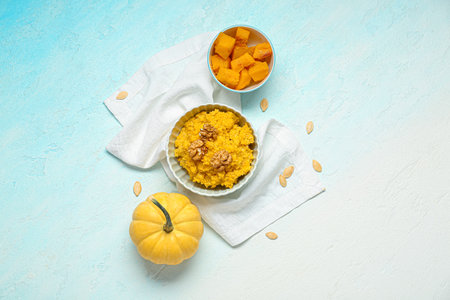 Bowl of tasty millet porridge with pumpkin and fresh vegetables on blue backgroundの写真素材