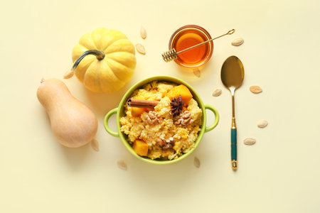 Pot of tasty millet porridge with pumpkin and ingredients on yellow backgroundの写真素材