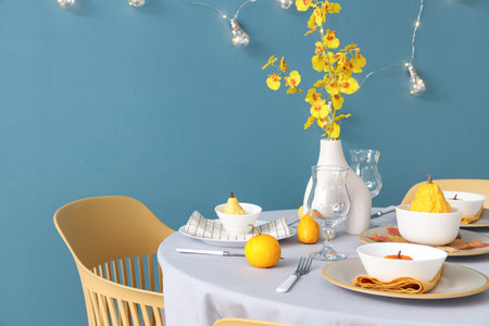 Autumn table setting with pumpkins and yellow flowers in festive roomの写真素材