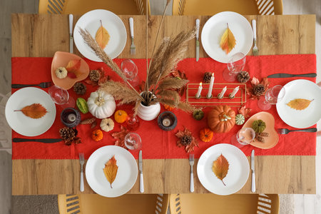 Autumn table setting with pumpkins, dry leaves and burning candlesの写真素材