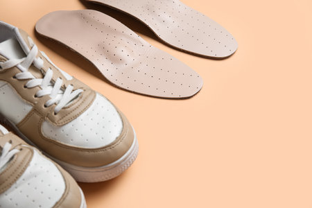 Pair of stylish sneakers and orthopedic insoles on color backgroundの写真素材