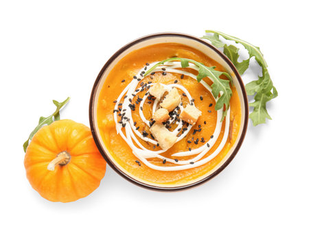 Bowl of delicious pumpkin cream soup with arugula and croutons on white backgroundの写真素材