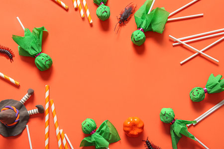 Frame made of sweet lollipops with candy bugs and straws for Halloween party on orange backgroundの写真素材