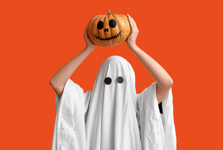 Young woman in Halloween costume of ghost holding pumpkin on color backgroundの写真素材