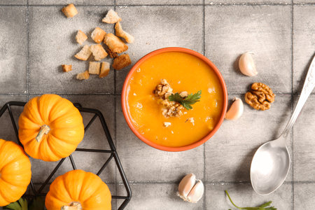Bowl of delicious pumpkin cream soup with walnut, parsley and croutons on gray tile backgroundの写真素材