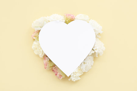 Paper heart with carnation flowers on yellow background. National Sweetest Dayの写真素材