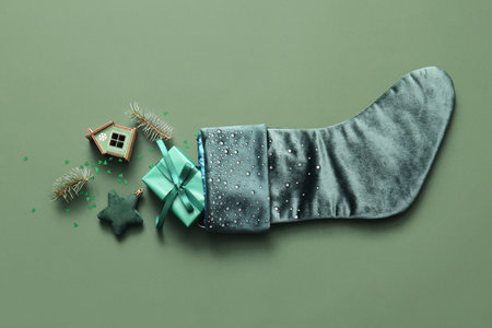 Beautiful Christmas sock with gift box and decorations on green backgroundの写真素材
