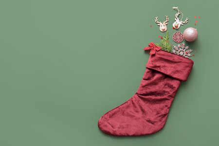 Beautiful Christmas sock with decorations on green backgroundの写真素材