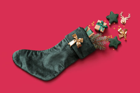 Beautiful Christmas sock with gift boxes and decorations on red backgroundの写真素材
