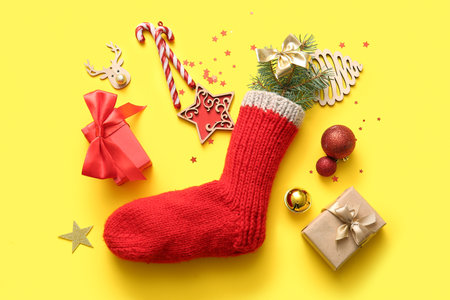 Beautiful Christmas sock with gift boxes and decorations on yellow backgroundの写真素材