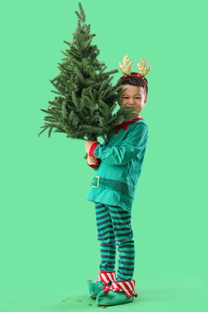Little Asian boy with Christmas tree on green backgroundの写真素材