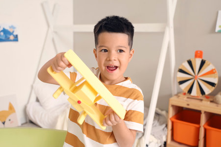 Little Asian boy playing with toy plane at homeの写真素材