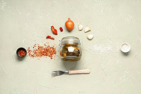 Jar with tasty pickled cucumbers and different spices on green backgroundの写真素材