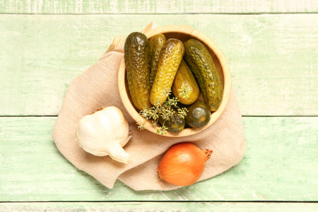 Bowl with tasty pickled cucumbers and onion and garlic on green wooden backgroundの写真素材
