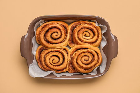 Baking dish of tasty cinnamon rolls on beige backgroundの写真素材