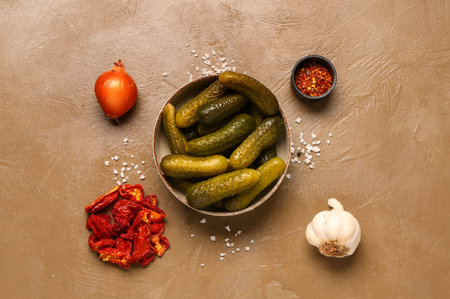 Bowl with tasty pickled cucumbers and different spices on brown backgroundの写真素材