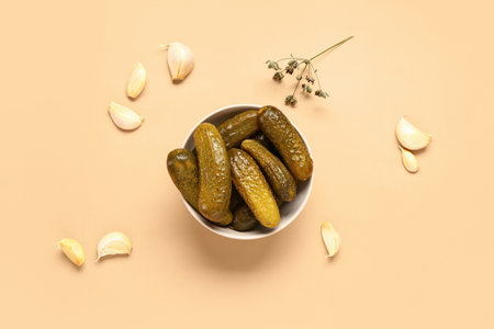 Bowl with tasty pickled cucumbers and garlic on orange backgroundの写真素材