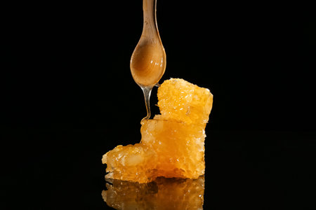 Sweet honeycombs and wooden spoon on black backgroundの写真素材