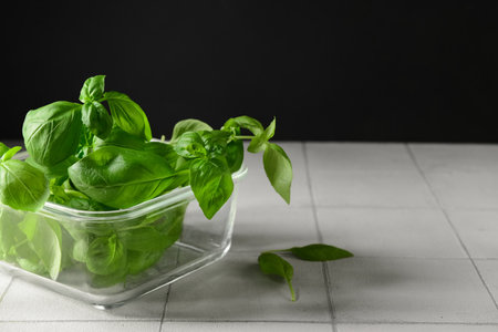 Glass bowl with fresh green basil on white tile tableの写真素材