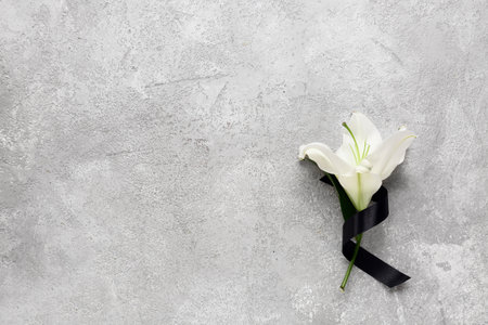 White lily flower with black ribbon on gray grunge backgroundの写真素材