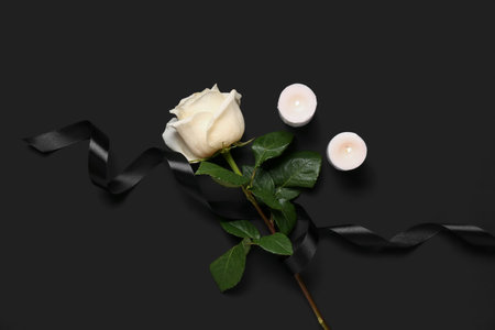 White rose with ribbon and burning candles on black backgroundの写真素材