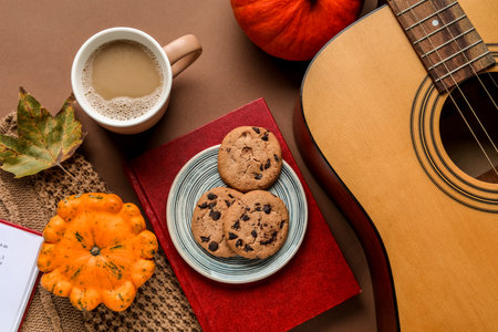 Composition with cup of coffee, guitar, book and pumpkins on color backgroundの写真素材