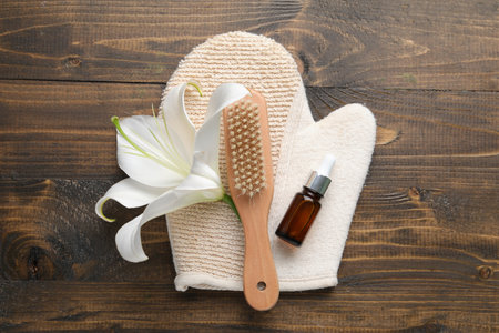 Massage glove, brush, essential oil and lily flower on wooden backgroundの写真素材