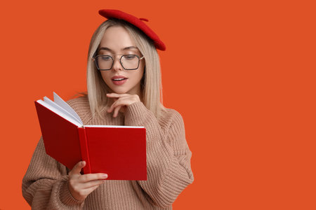 Beautiful young woman reading book on red backgroundの写真素材