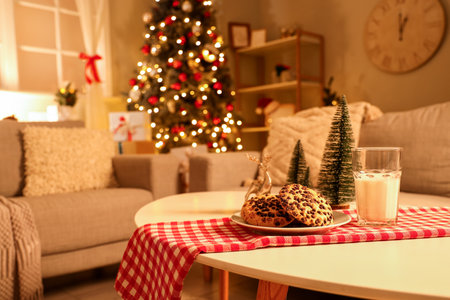 Christmas cookies with glass of milk and decor on table in living room at nightの写真素材