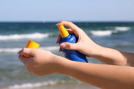 Young woman applying sunscreen cream on body at resortの写真素材