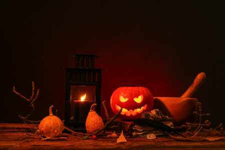 Halloween composition with jack-o-lantern, pumpkins and tree branches on wooden tableの写真素材