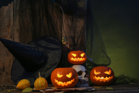 Halloween composition with jack-o-lanterns, skull and witch hat on wooden tableの写真素材
